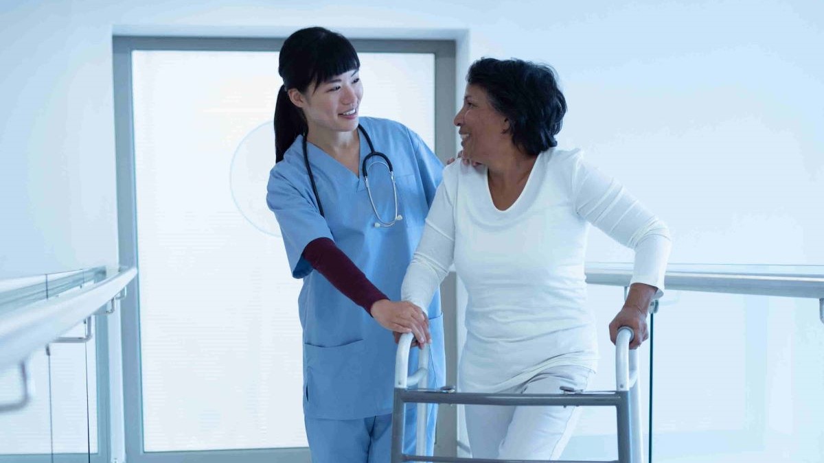 Une professionnelle de santé accompagne une dame qui marche avec un déambulateur